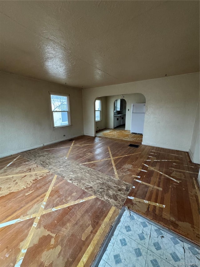 spare room featuring arched walkways, a textured ceiling, and visible vents