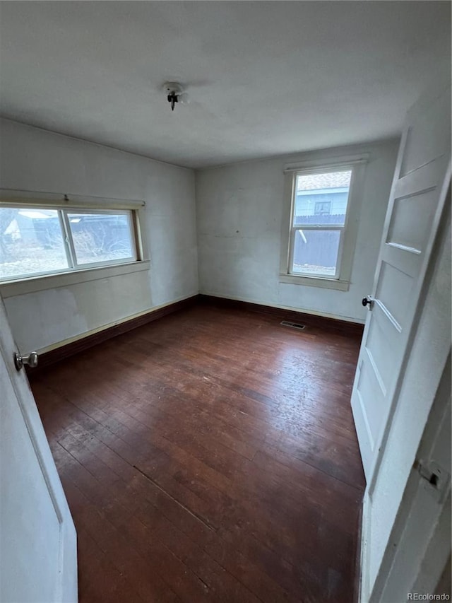 interior space featuring multiple windows, dark wood-style flooring, visible vents, and baseboards