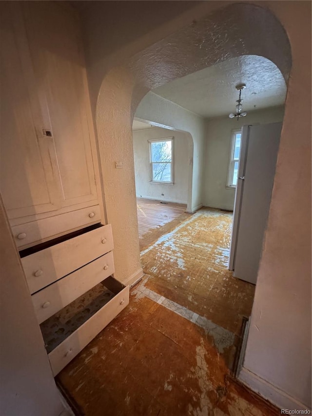 corridor featuring arched walkways and a textured wall