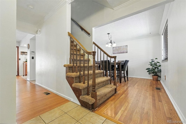 7314 W Walker Pl, Littleton, CO 80123 - staircase featuring wood finished floors, visible vents, a chandelier, and ornamental molding
