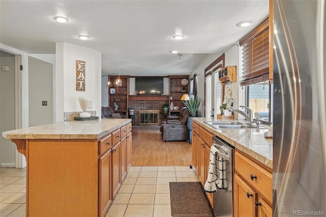 7314 W Walker Pl, Littleton, CO 80123 - kitchen featuring a sink, open floor plan, light tile patterned flooring, stainless steel appliances, and a fireplace