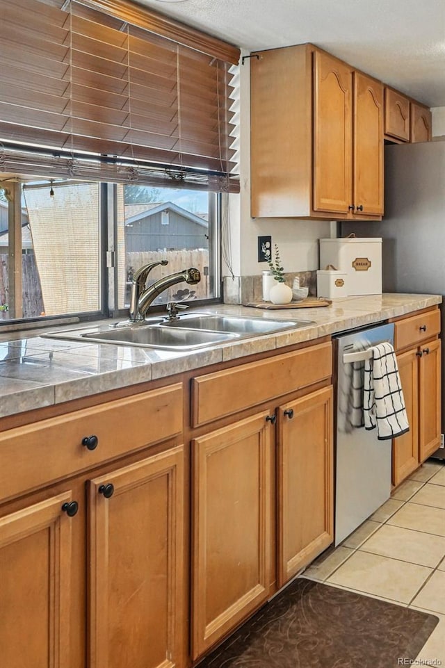 7314 W Walker Pl, Littleton, CO 80123 - kitchen with light countertops, light tile patterned flooring, brown cabinetry, dishwasher, and a sink