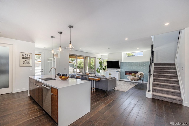4180 Ames St, Denver, CO 80212 - kitchen with dark wood-style flooring, a glass covered fireplace, light countertops, a kitchen island with sink, and dishwasher