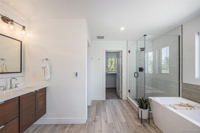 4180 Ames St, Denver, CO 80212 - bathroom with vanity, a shower stall, a freestanding tub, and wood finished floors