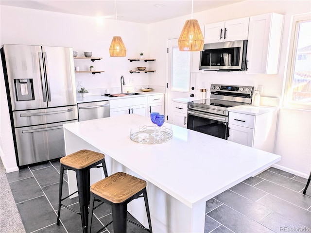 kitchen with white cabinets, a center island, appliances with stainless steel finishes, and sink