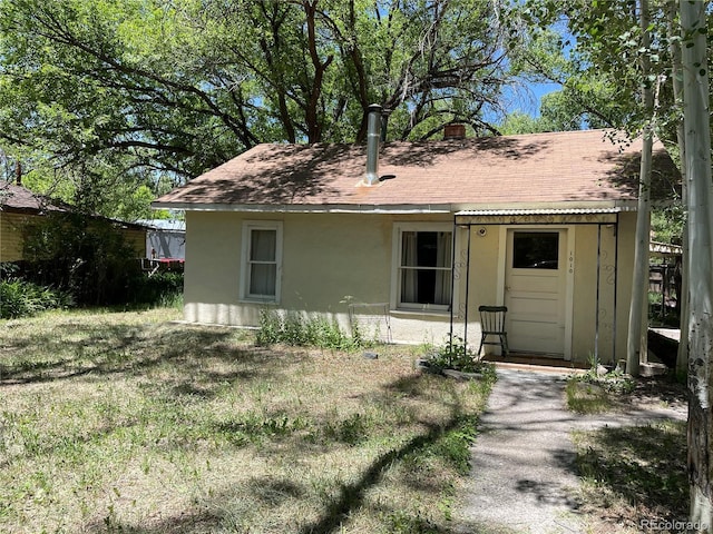 1010 San Juan Ave, Saguache, CO 81149 - view of front facade featuring stucco siding, a shingled roof, and a front yard