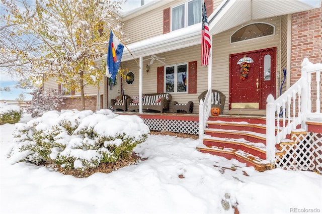 snow covered property entrance featuring a porch and ceiling fan