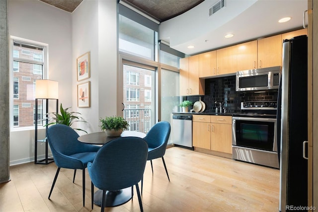 kitchen with tasteful backsplash, stainless steel appliances, light hardwood / wood-style flooring, and light brown cabinets