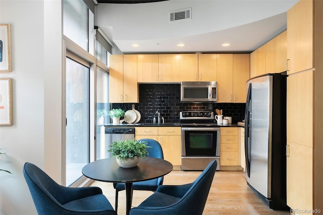 kitchen with light brown cabinetry, sink, appliances with stainless steel finishes, light hardwood / wood-style floors, and decorative backsplash