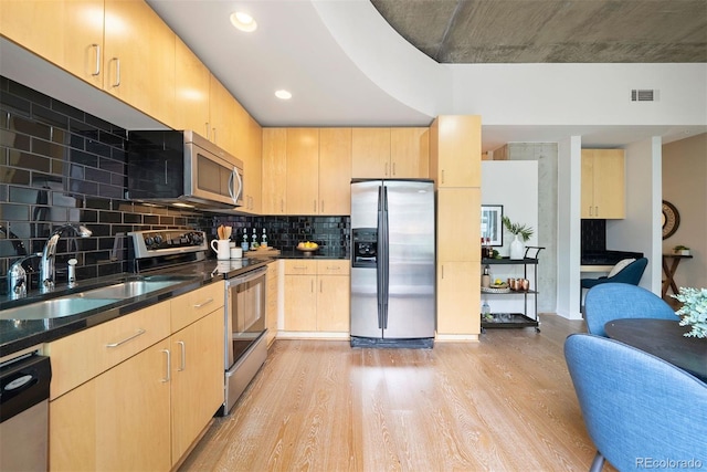 kitchen with light brown cabinetry, sink, light wood-type flooring, appliances with stainless steel finishes, and decorative backsplash