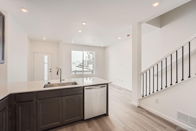 kitchen with kitchen peninsula, dark brown cabinetry, sink, light hardwood / wood-style flooring, and stainless steel dishwasher