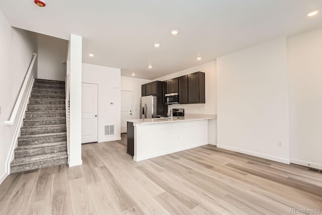 kitchen featuring stainless steel appliances, light wood-type flooring, and kitchen peninsula