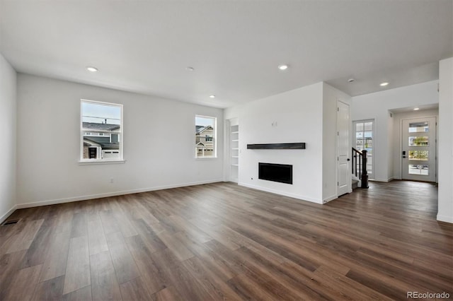 24708 E 40th Ave, Aurora, CO 80019 - unfurnished living room featuring dark wood-style floors, recessed lighting, baseboards, a fireplace, and built in shelves
