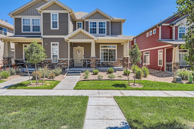 craftsman house featuring board and batten siding, a front yard, covered porch, and stone siding