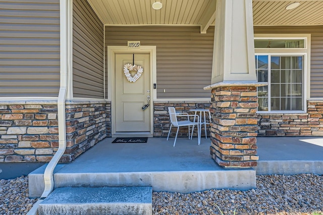 entrance to property with stone siding and a porch