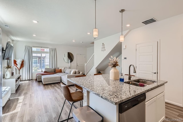 kitchen featuring white cabinets, open floor plan, decorative light fixtures, stainless steel dishwasher, and a sink