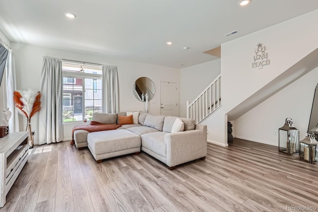 living area featuring light wood-type flooring, baseboards, stairway, and recessed lighting