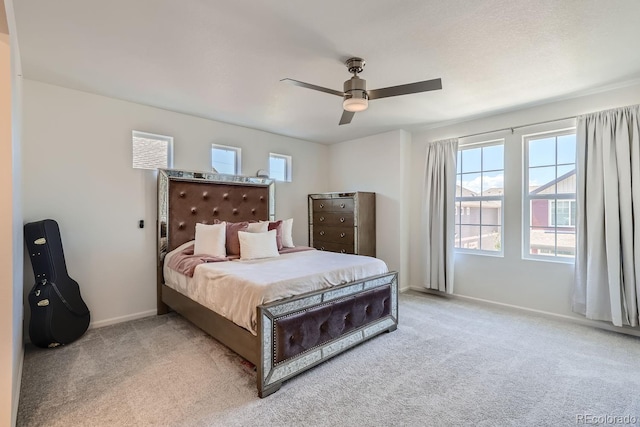 bedroom with light colored carpet, ceiling fan, baseboards, and multiple windows