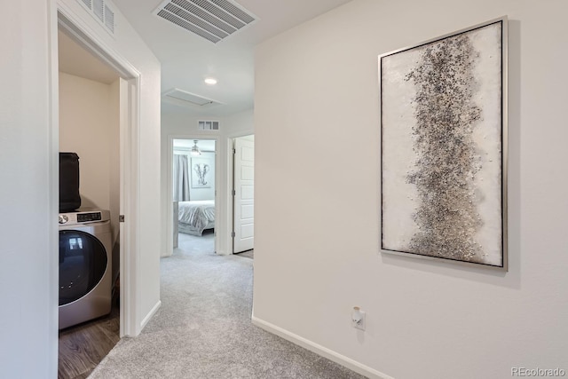 corridor with washer / dryer, attic access, visible vents, baseboards, and carpet flooring