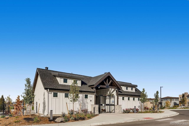 modern inspired farmhouse featuring a residential view, fence, board and batten siding, and roof with shingles