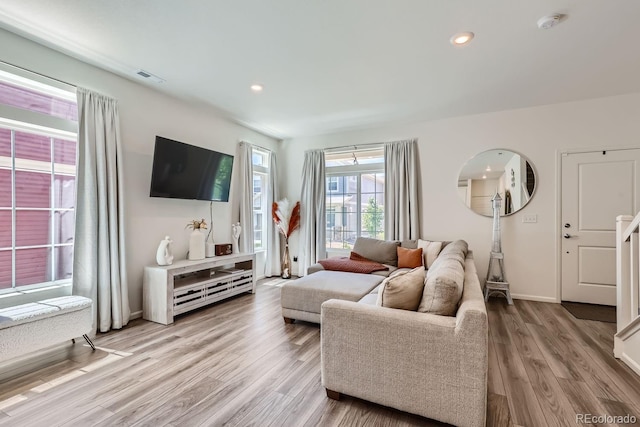 living area featuring baseboards, light wood finished floors, visible vents, and recessed lighting