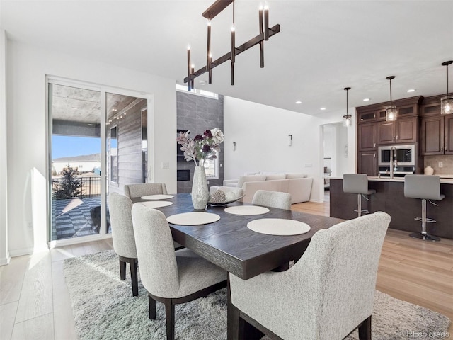 dining room featuring sink, light hardwood / wood-style flooring, and a notable chandelier