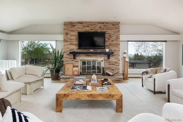 living area with a baseboard heating unit, vaulted ceiling, a stone fireplace, and wood finished floors