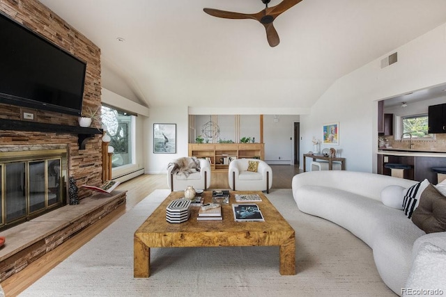 living room with visible vents, lofted ceiling, a fireplace, a ceiling fan, and a wealth of natural light