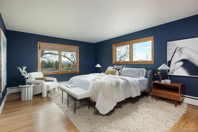 bedroom with baseboards, multiple windows, and wood finished floors