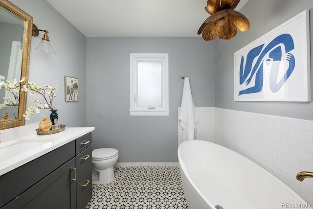 bathroom with vanity, toilet, baseboards, tile patterned floors, and a freestanding bath
