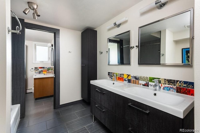 full bath with double vanity, a bathtub, a sink, and a baseboard radiator