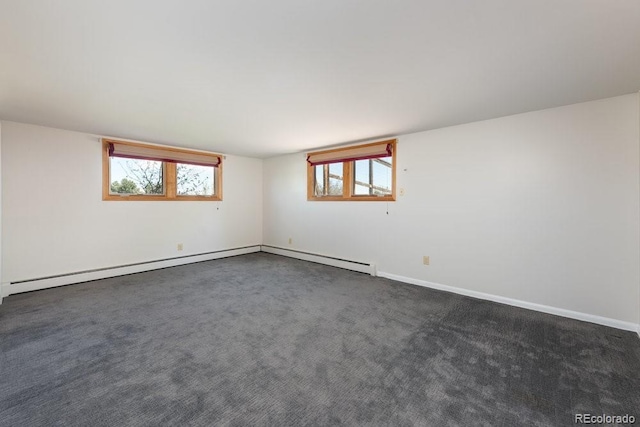 unfurnished room featuring baseboard heating, baseboards, a healthy amount of sunlight, and dark colored carpet