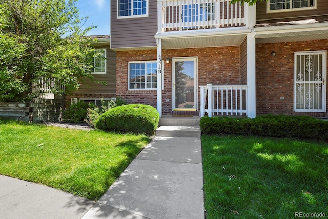 4574 S Cimmarron Cir Unit B, Aurora, CO 80015 - property entrance with covered porch, brick siding, and a yard