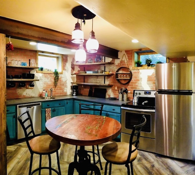 8211 Rocky Mountain Dr, Lakewood, CO 80214 - kitchen featuring stainless steel appliances, open shelves, dark countertops, light wood-style flooring, and brick wall
