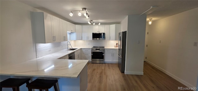775 S Alton Way Unit 4A, Denver, CO 80247 - kitchen with a peninsula, stainless steel appliances, light stone counters, backsplash, and wood finished floors