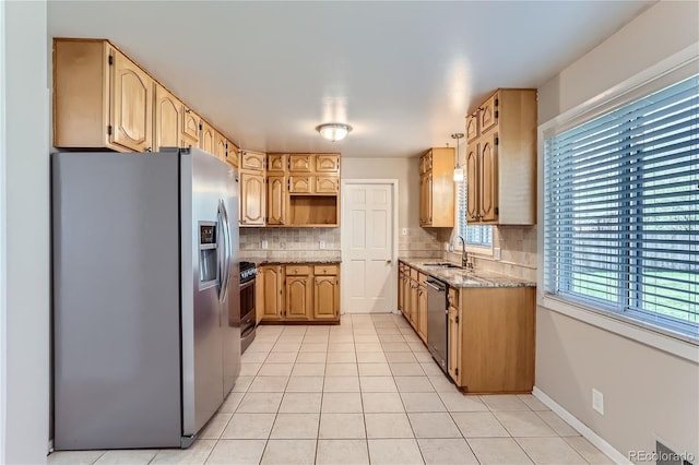 kitchen with backsplash, stainless steel appliances, sink, light stone countertops, and light tile patterned floors