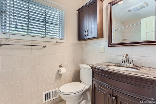 bathroom with toilet, vanity, and tile walls