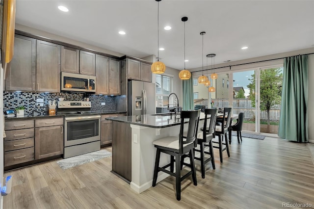 kitchen featuring a sink, appliances with stainless steel finishes, dark countertops, and a kitchen bar