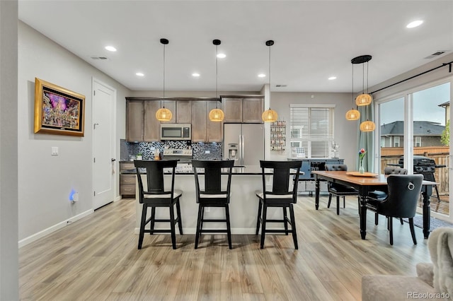 kitchen featuring appliances with stainless steel finishes, light wood-type flooring, visible vents, and tasteful backsplash