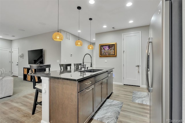 kitchen featuring a sink, light wood finished floors, a breakfast bar area, stainless steel appliances, and open floor plan
