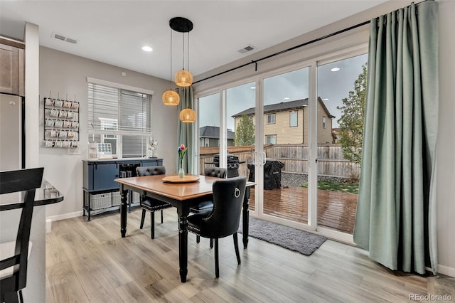 dining space with plenty of natural light, light wood finished floors, and visible vents