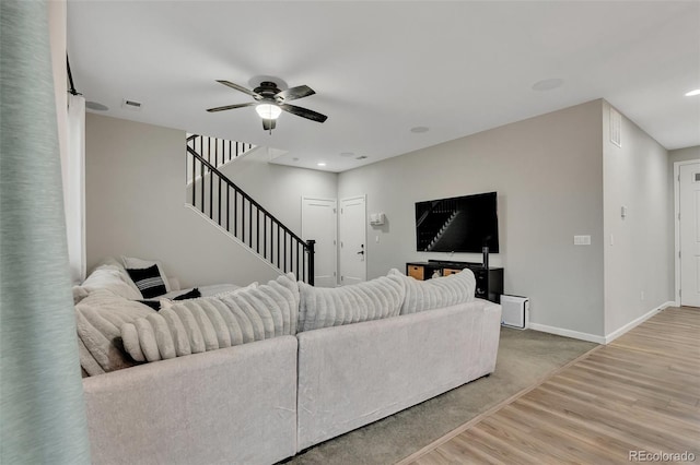 living room with visible vents, stairs, wood finished floors, baseboards, and ceiling fan