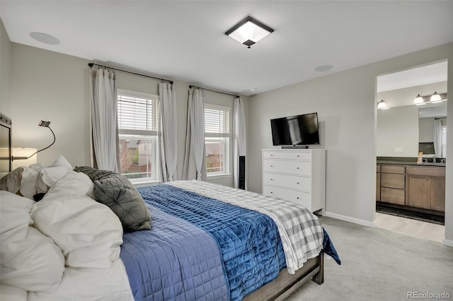 bedroom featuring baseboards, light carpet, and ensuite bath