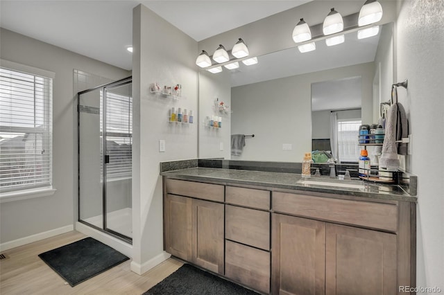 full bathroom with vanity, baseboards, a stall shower, and wood finished floors