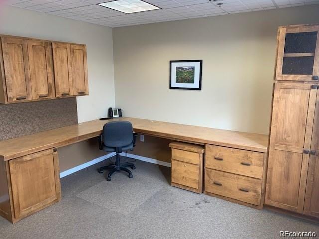 home office featuring a paneled ceiling, light carpet, and built in desk