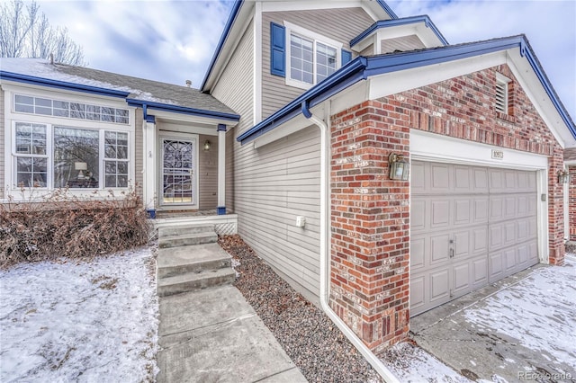 snow covered property entrance with a garage