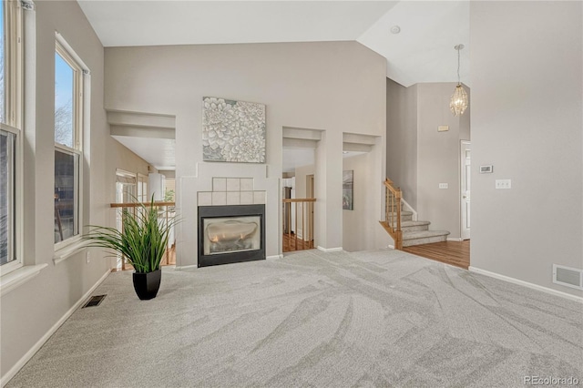 carpeted living room featuring a tile fireplace and high vaulted ceiling