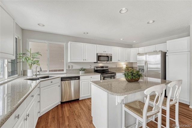 kitchen featuring white cabinetry, appliances with stainless steel finishes, sink, and light stone counters