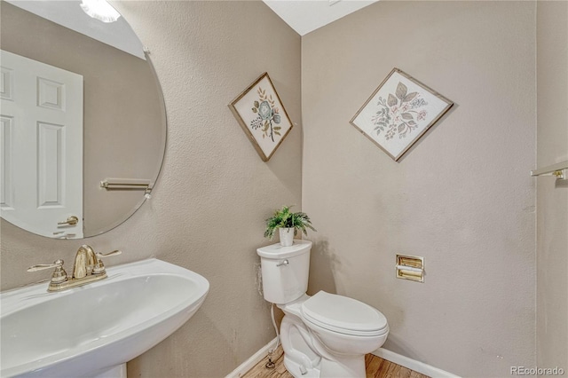 bathroom featuring wood-type flooring, toilet, and sink