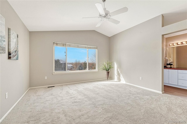 unfurnished bedroom with lofted ceiling, ensuite bath, ceiling fan, and carpet